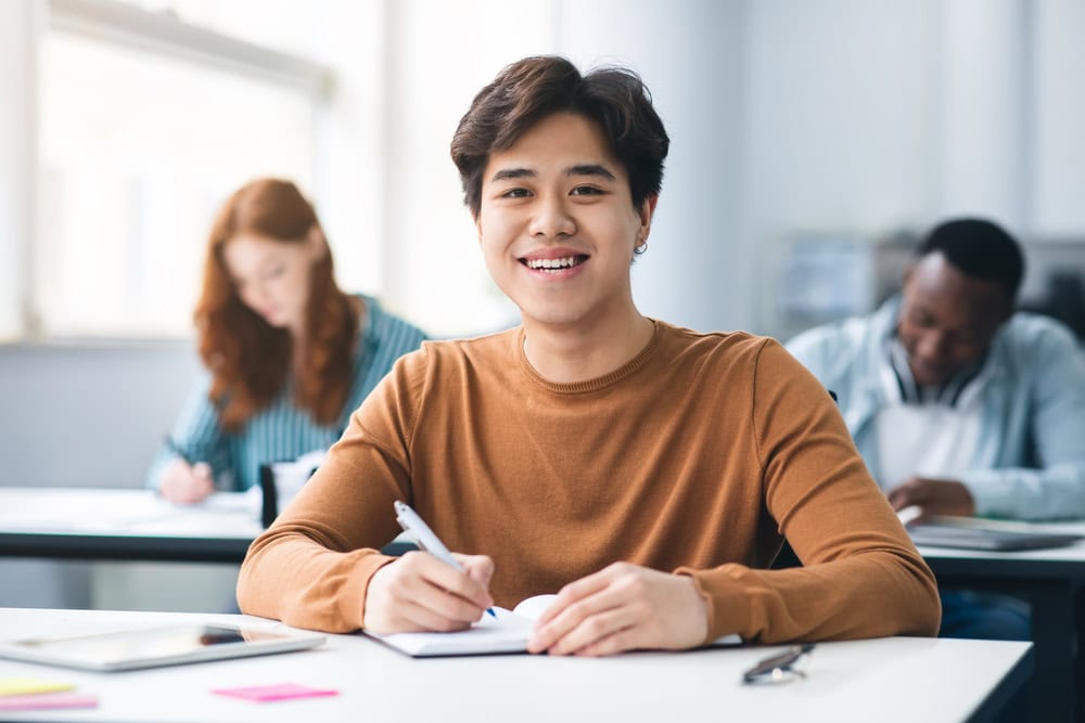 Joven en clase universitaria tomando notas, ambiente de estudio académico y motivador.